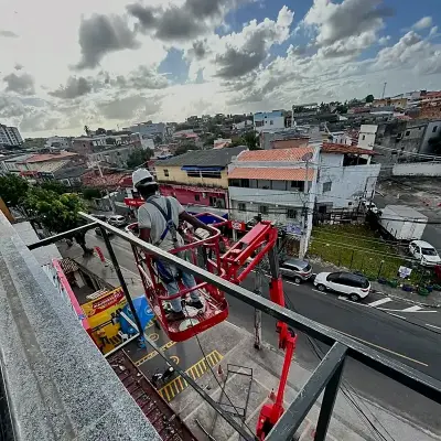 Instalador na cesta da plataforma articulada trabalhando nos pavimentos superiores da fachada da B3 Fitness